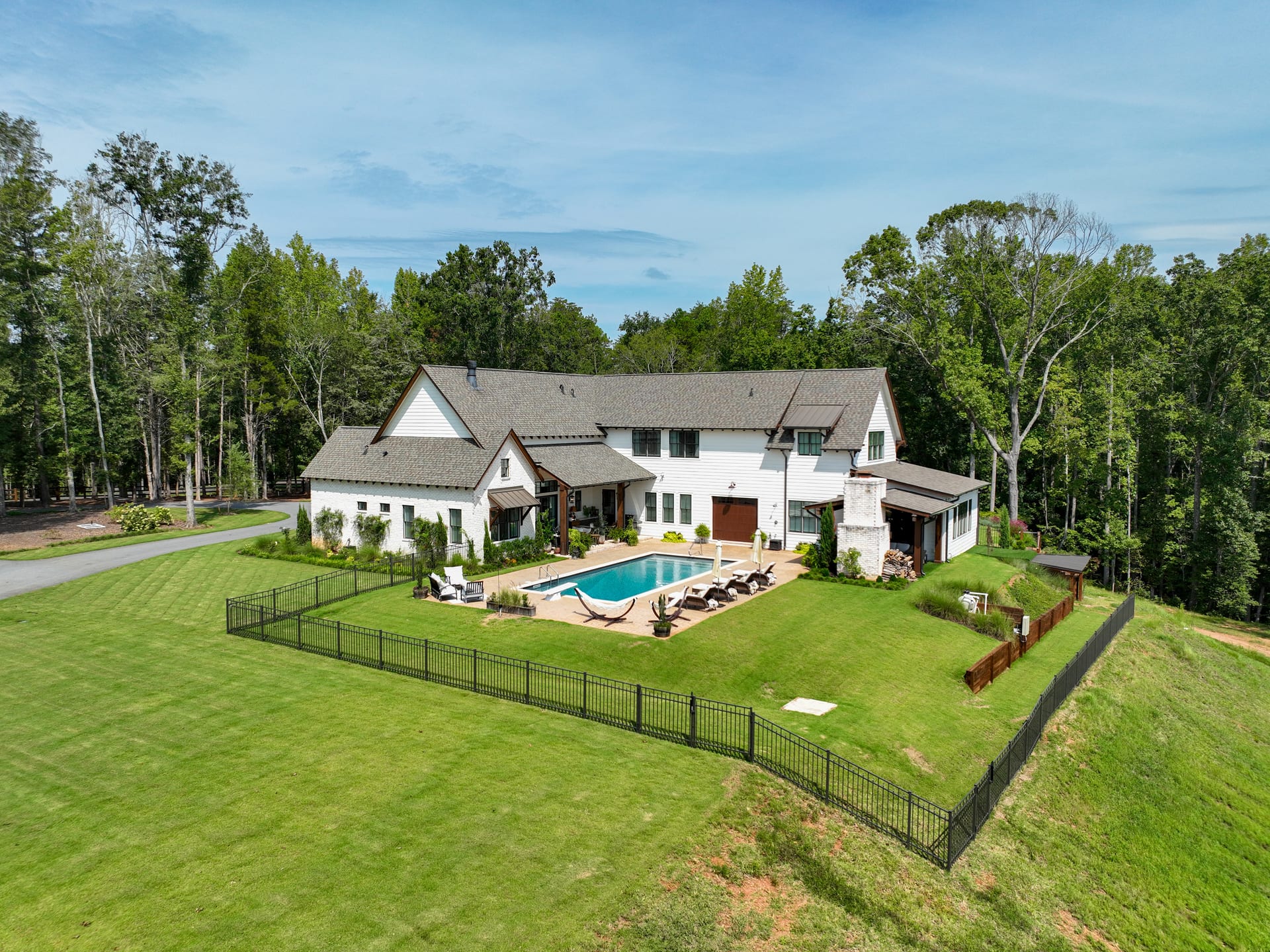 The Newton farmhouse from above — pool, fenced yard, and mature canopy.