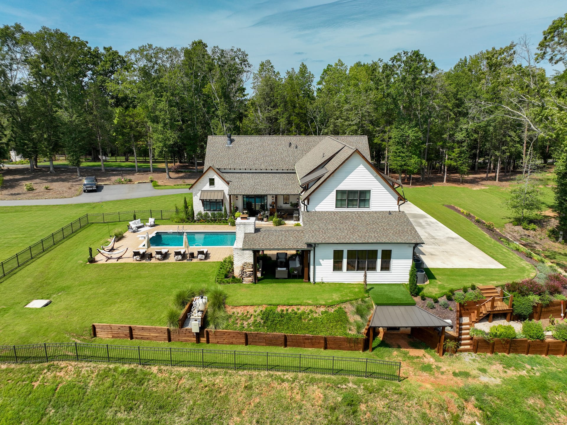 Rear elevation reveals the pool deck nestled into a wooded lot.