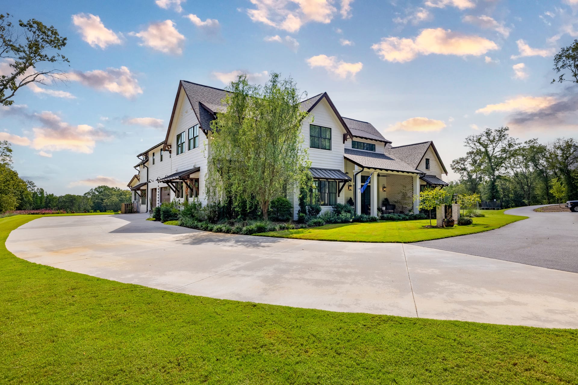 Golden sunset washes over the farmhouse exterior and gravel drive.