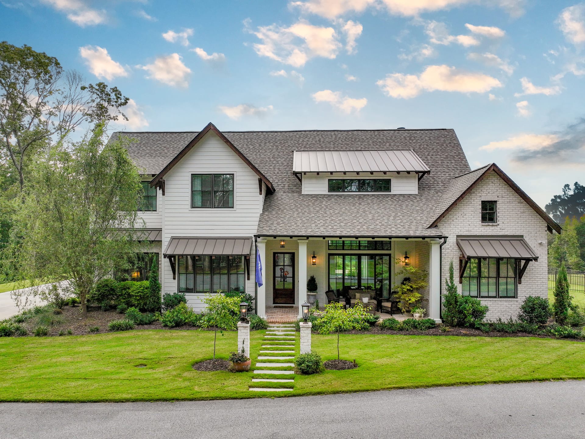 Metal awnings and a landscaped walkway welcome guests to the front door.