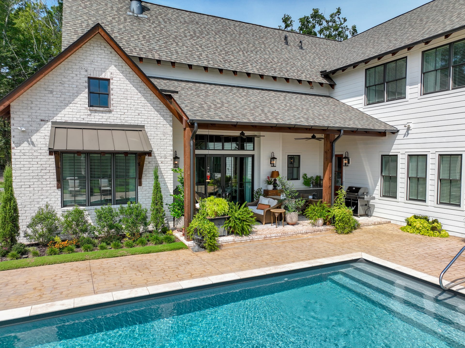 Covered porch and brick gable frame the pool in architectural warmth.