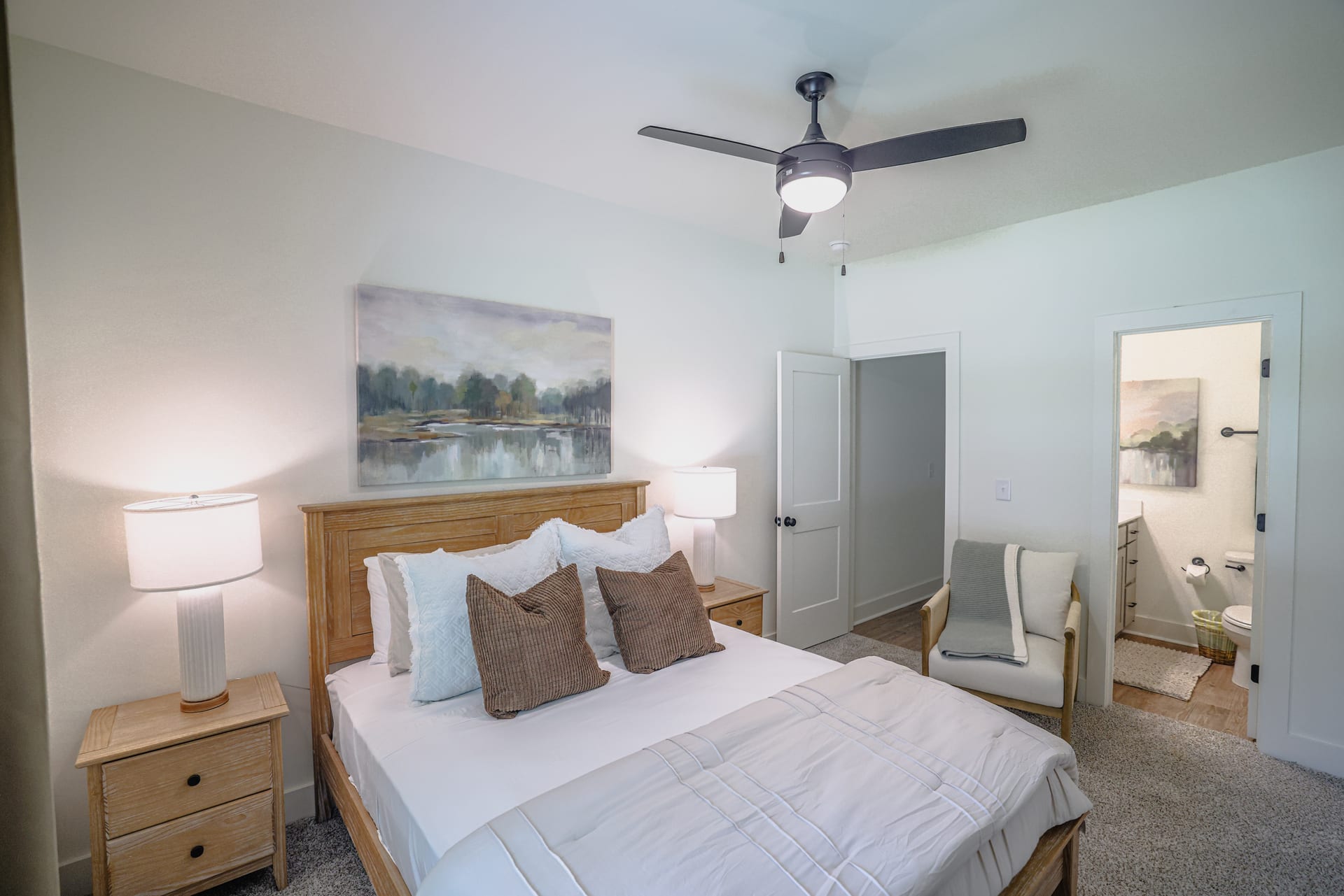 Oak-framed bed and lake-inspired artwork set a serene guest retreat.