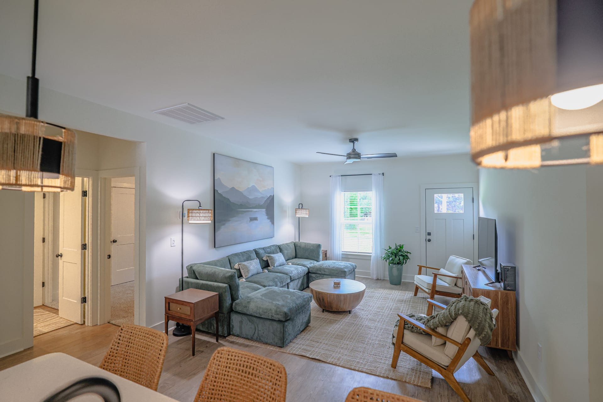 Sage sofa beneath a mountain canvas — layered tones grounding the living room.