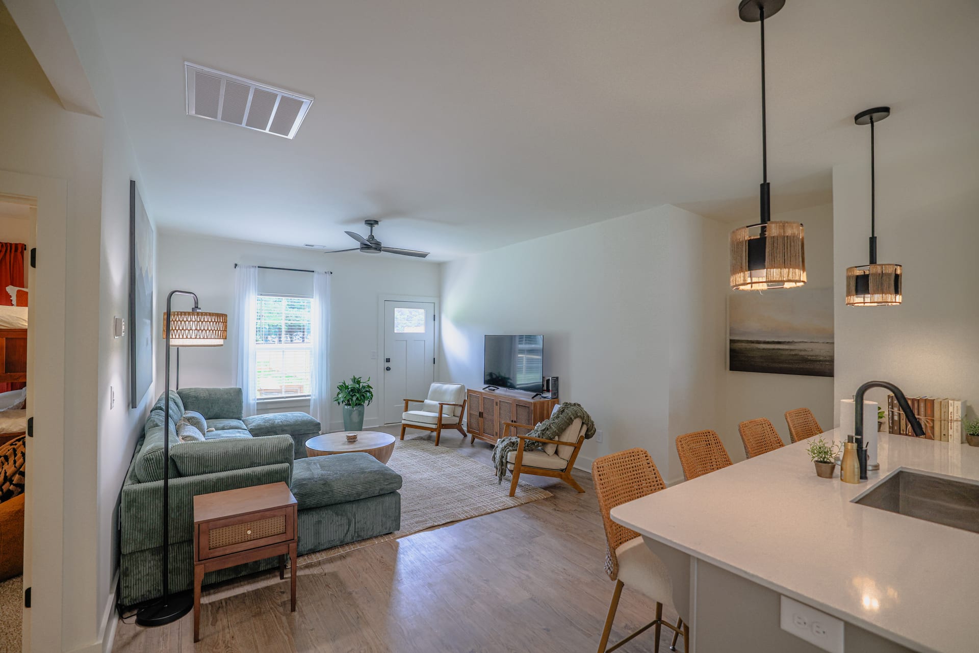 Open-plan living flows from sage sectional through to the kitchen bar.
