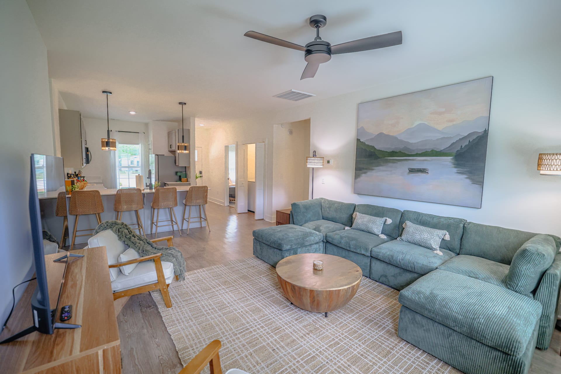 A teal sectional and round wood coffee table define an inviting gathering space.