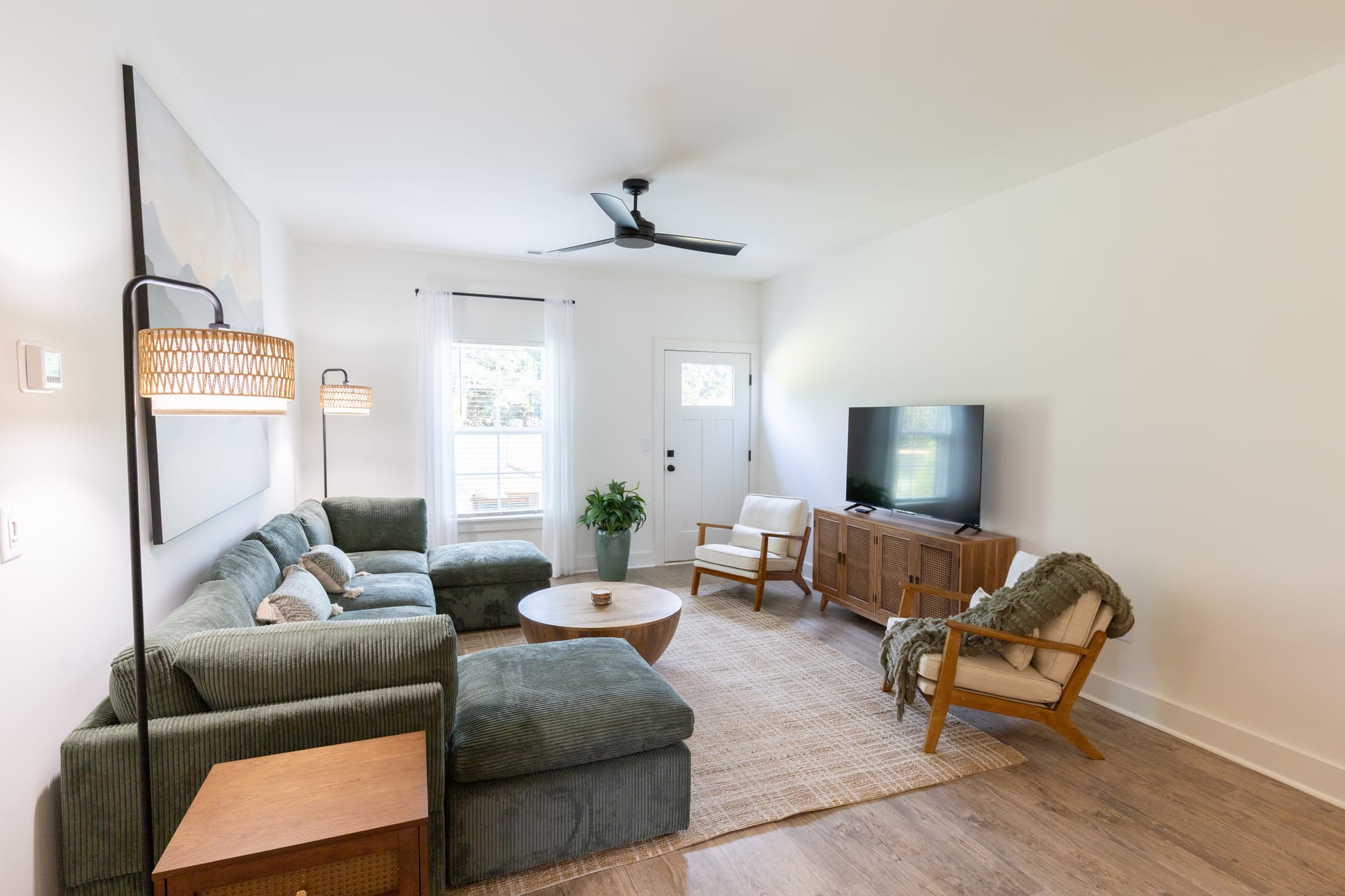 Rattan lamps flank the console as the green sectional anchors the living space.
