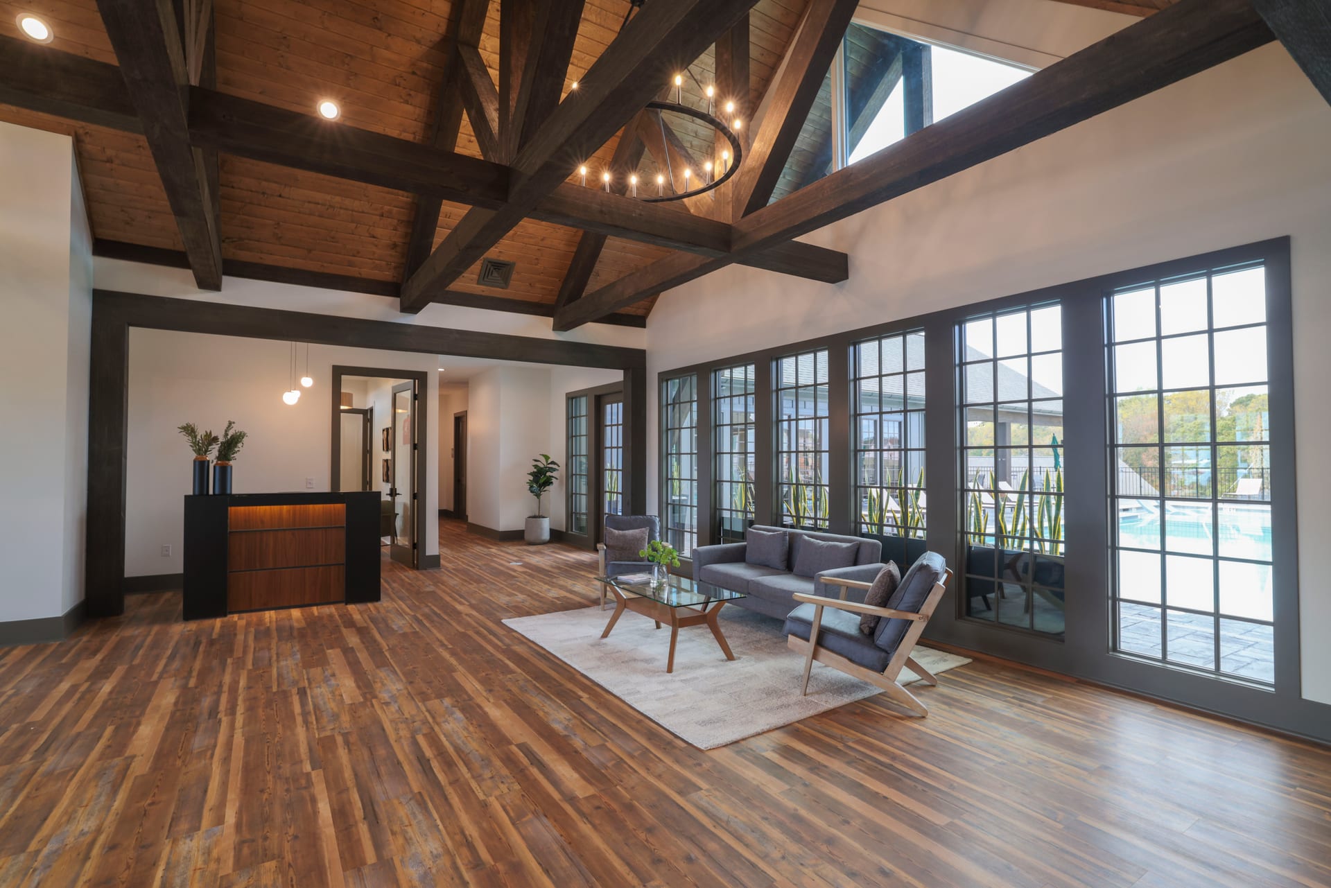 Grand chandelier and hardwood floors open onto a shimmering pool view.