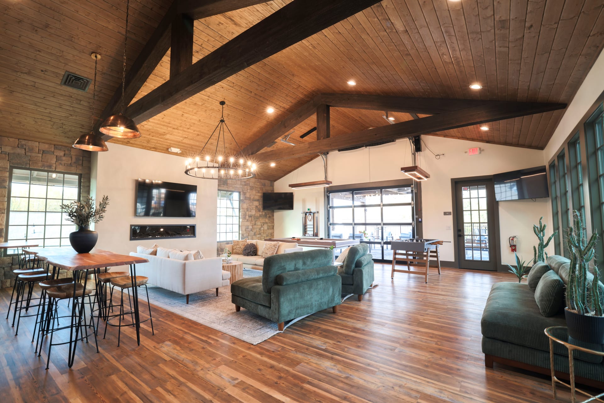 Wide lounge panorama — vaulted timber ceiling meeting stone and soft seating.