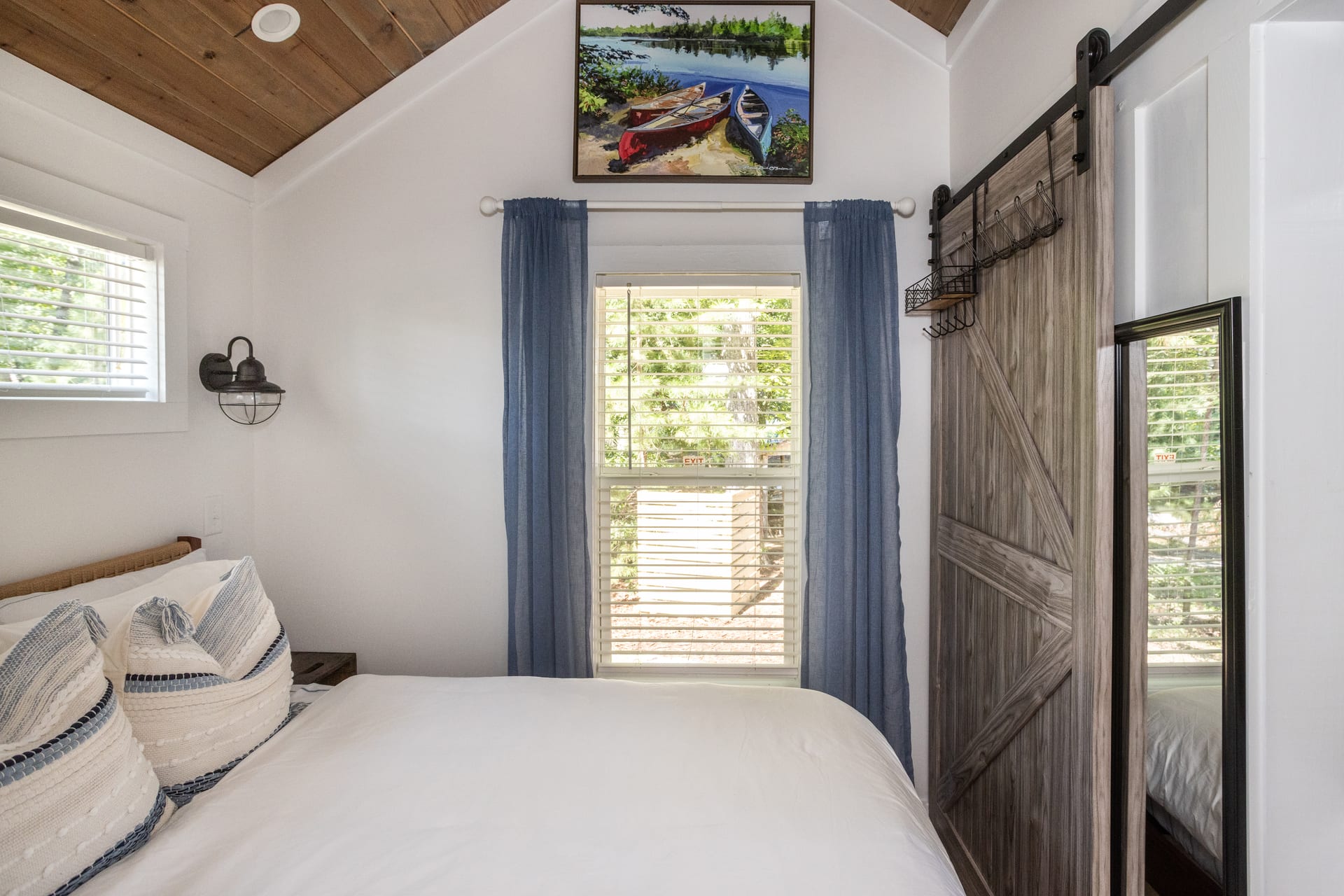 Barn door mirror and canoe painting evoke lakeside living in the bedroom.