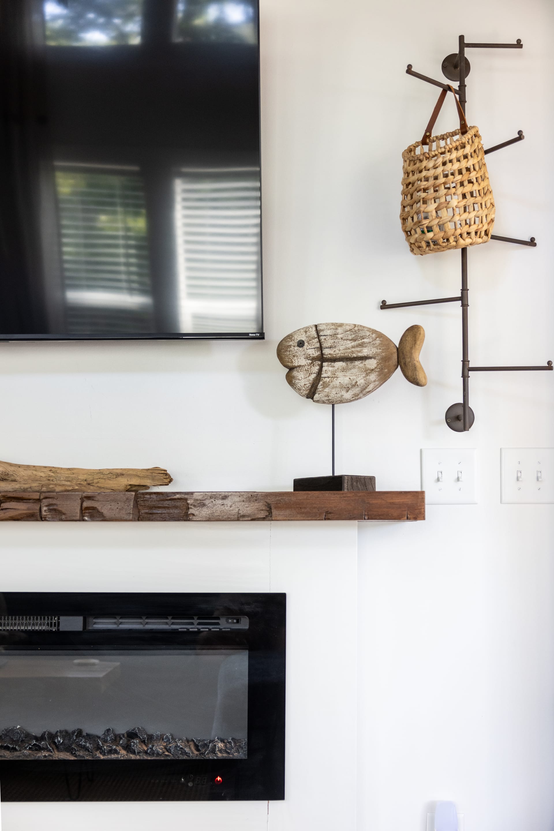 Carved fish and driftwood adorn the mantel — nature as art.
