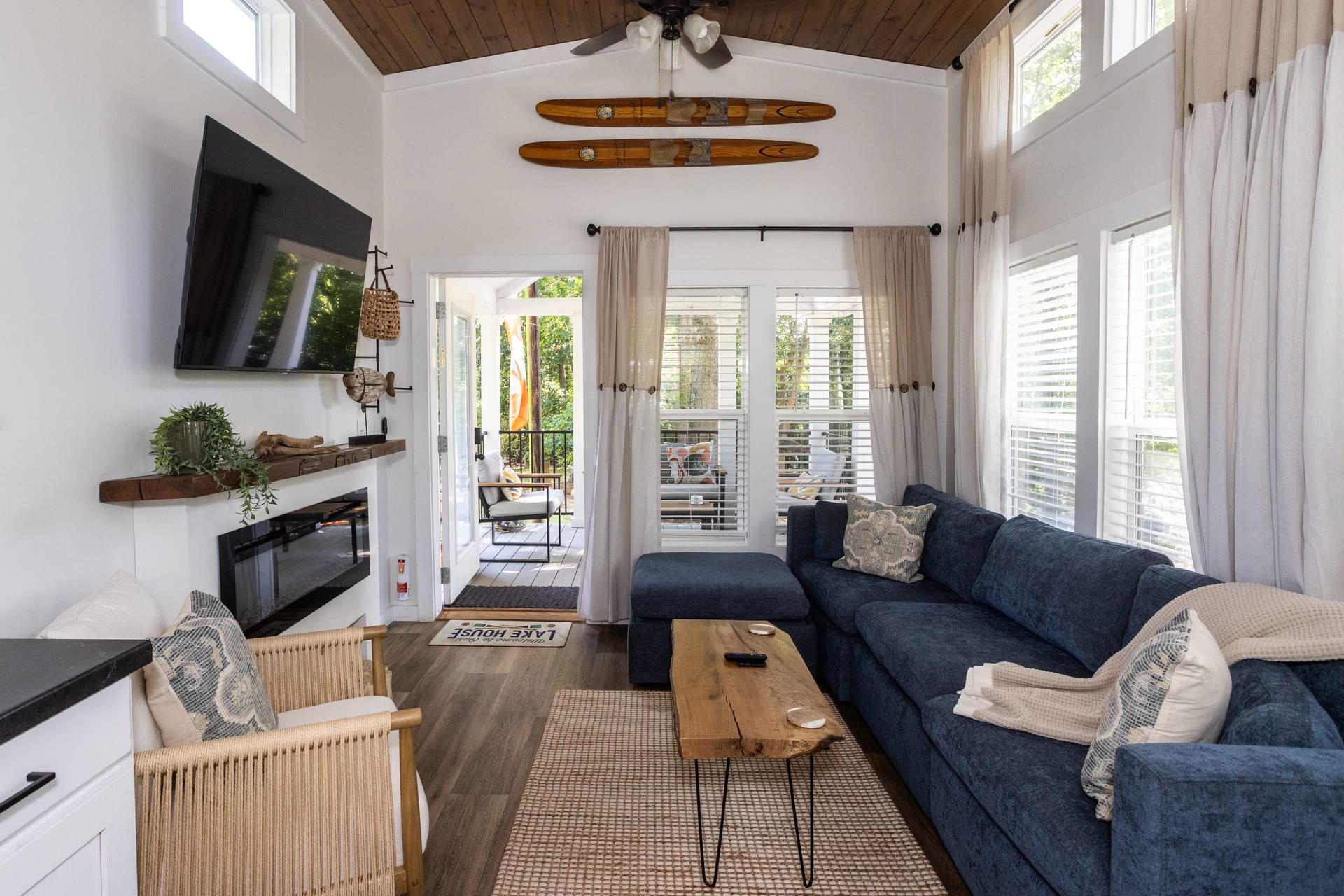 Rattan chair and navy sectional circle the hearth in layered warmth.