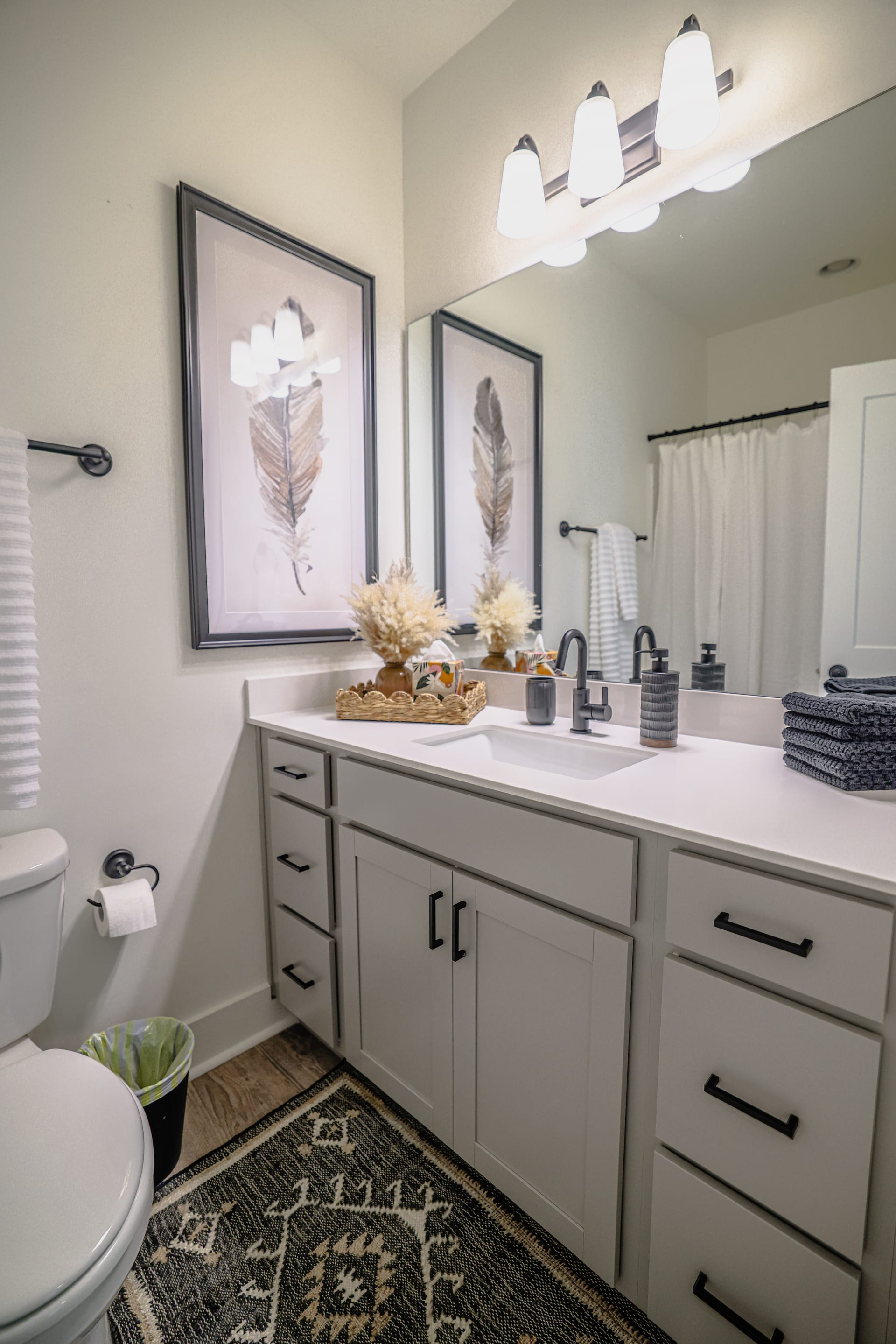Feather art and navy towels bring personality to a crisp bathroom vanity.