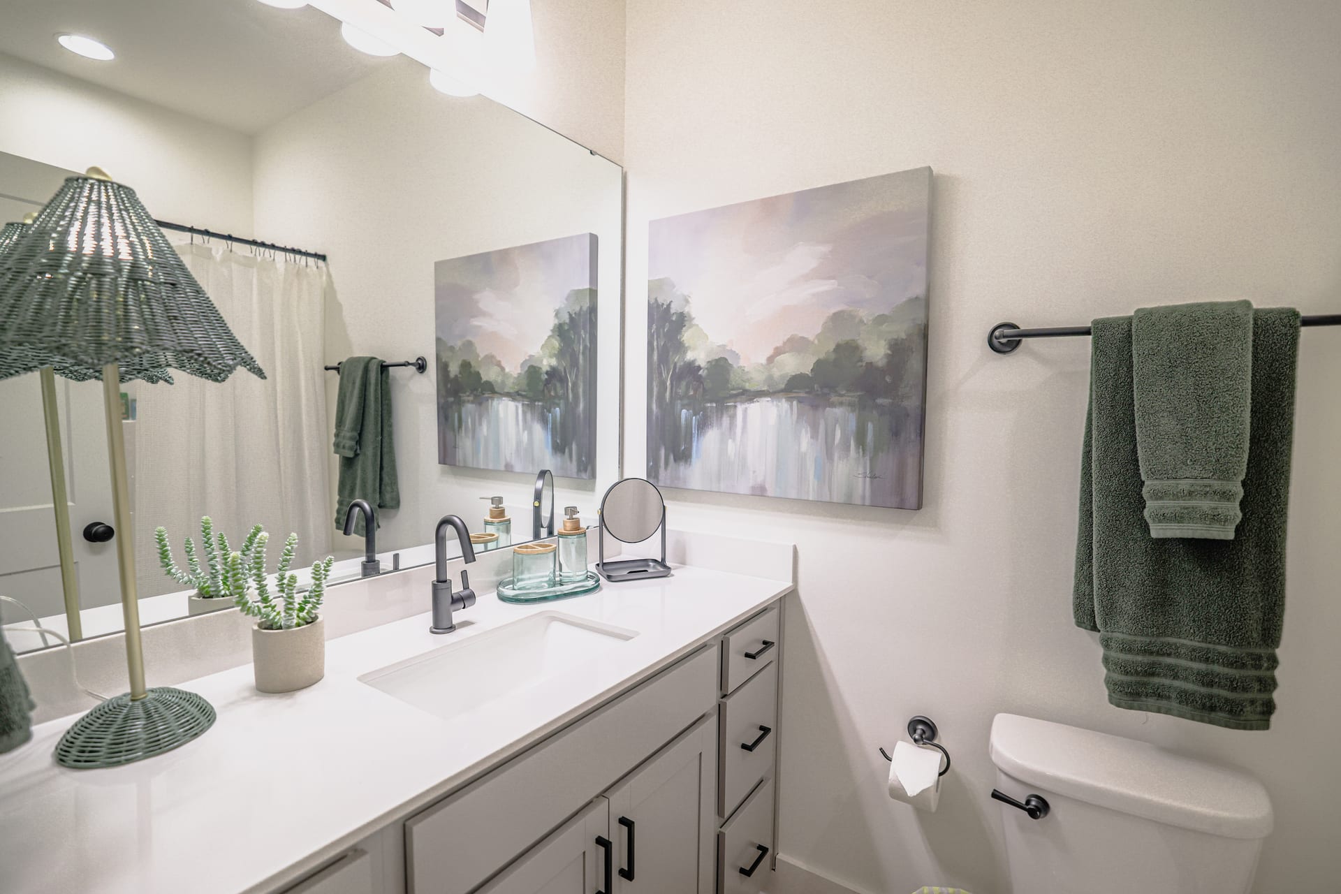Green accent vanity and landscape painting infuse the bath with earthy calm.