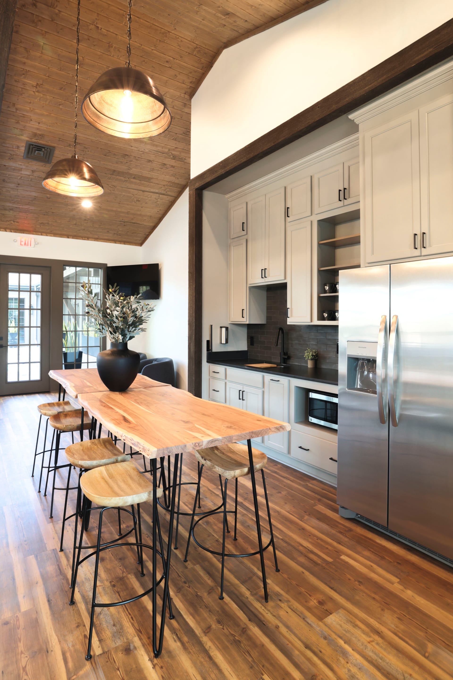 Copper pendants hang from vaulted timber above the kitchen bar stools.