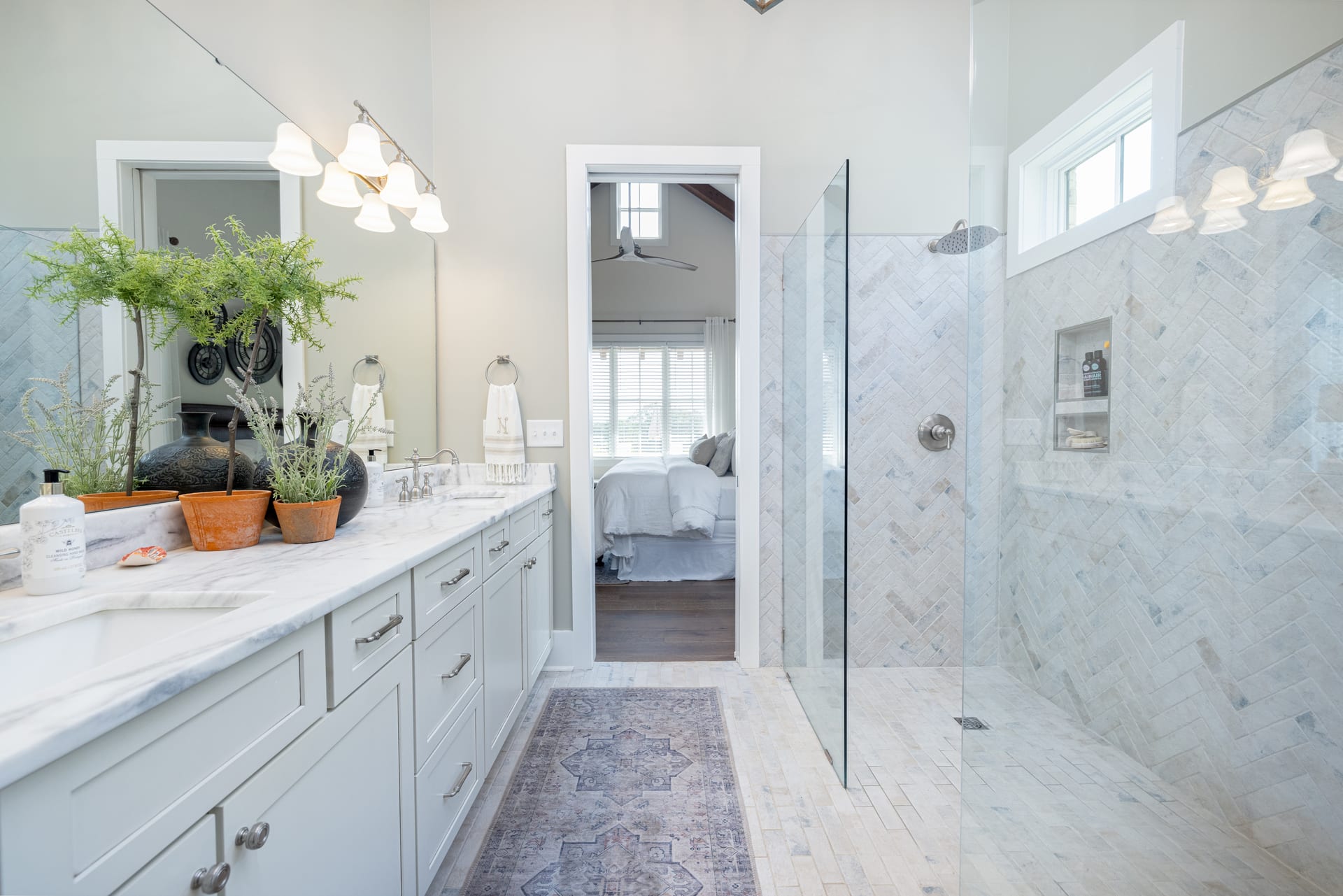 Marble herringbone and frameless glass define the master bath sanctuary.