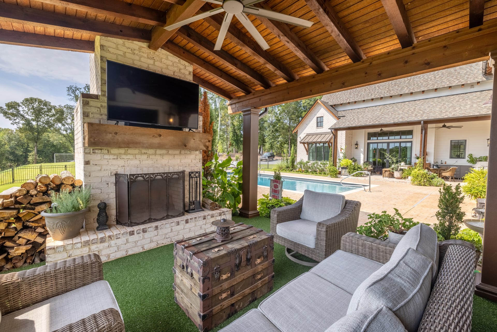 Brick fireplace and wicker seating overlook the pool from the covered patio.